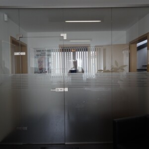 sklenená stena s otočnými dverami z číreho skla s polepom