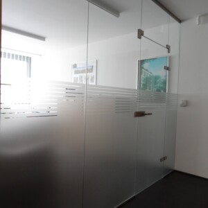 sklenená stena s otočnými dverami z číreho skla s polepom