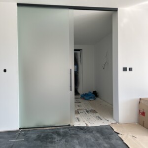 sklenená stena s posuvnými dverami z matného skla