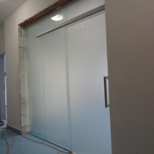 sklenená stena s posuvnými dverami z matného skla