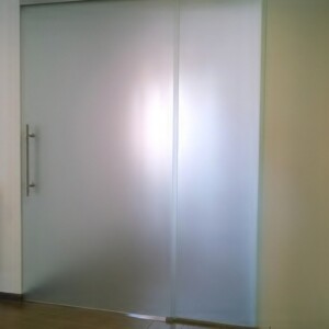 sklenená stena s posuvnými dverami z matného skla