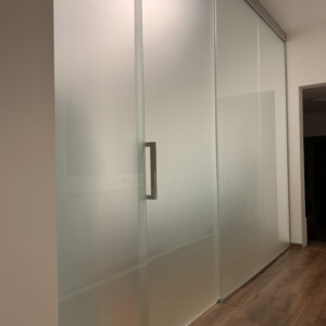 sklenená stena s posuvnými dverami z matného skla